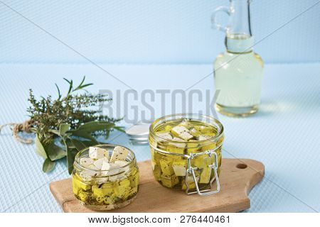 Marinated Feta In A Glass Jar And Spices Against Blue Background