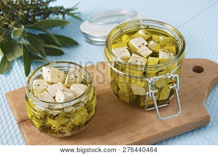 Marinated Feta In A Glass Jar And Spices Against Blue Background