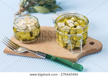 Marinated Feta In A Glass Jar And Spices Against Blue Background
