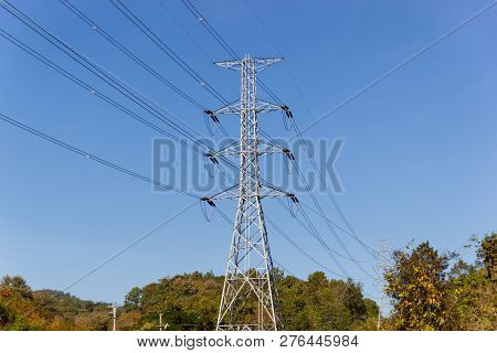 High Voltage Transmission Towers With Mountain Background And Blue Sky