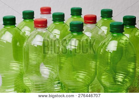 Many Green Plastic Bottles With Caps. Production Of Beverages In Plastic Containers. Problem Of Envi