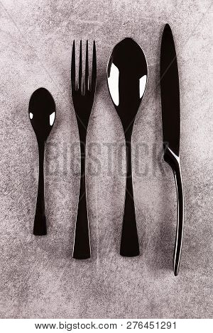 Modern Black Cuttlery On Grey Surface From Above.