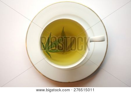 Cannabis Tea. Marijuana Tea. Hemp Tea with a Marijuana Leaf in a white Tea Cup. Isolated on white. Room for text. 