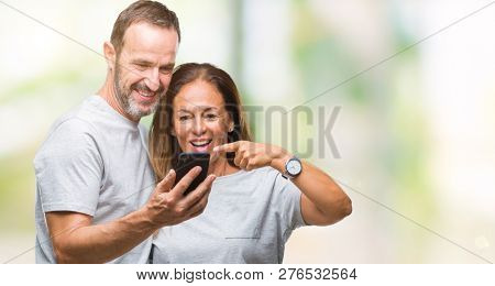 Middle age hispanic couple texting message on smartphone ver isolated background very happy pointing with hand and finger