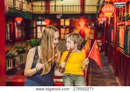Enjoying Vacation In China. Happy Tourists Mom And Son With A Chinese Flag And With Traditional Chin