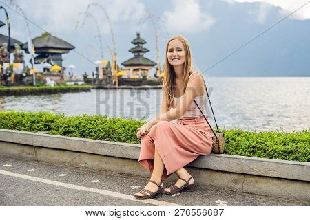 Young Woman Traveler In The Background Of Pura Ulun Danu Bratan, Bali. Hindu Temple Surrounded By Fl