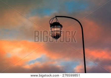 Old Street Lamp On The Background Of A Blocky Sky Suspended On An Iron Rusty Curved Tube