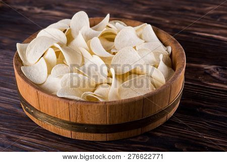 Potato Chips Lie In A Light Oak Tray On A Dark Table.