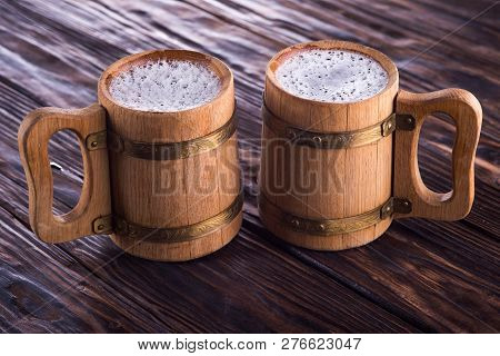Two Oak Mugs With Beer Inside. On Dark Wooden Background