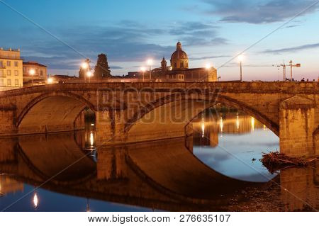 FLORENCE, ITALY - AUGUST 7, 2018: Night view to Ponte alla Carraia bridge and the church San Frediano di Cestello. The current bridge was completed in 1948 after the blowing up during WWII