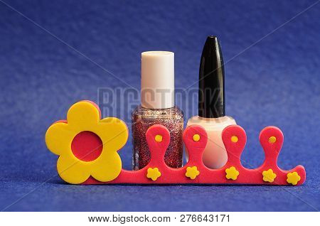 Nail Polish And A Toe Separator On A Blue Background