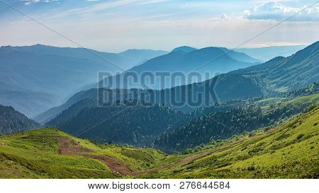The View From The Height Of A Green Mountain Valley With Residential Buildings Surrounded By High Mo
