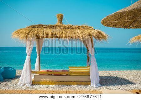 Sunshade Umbrellas And Deckchairs On The Beautiful Beach In Himara, Turquoise Water Of Ionian Sea In