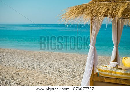 Sunshade Umbrellas And Deckchairs On The Beautiful Beach In Himara, Turquoise Water Of Ionian Sea In
