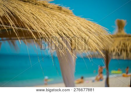 Sunshade Umbrellas And Deckchairs On The Beautiful Beach In Himara, Turquoise Water Of Ionian Sea In
