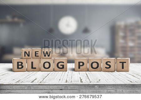 New Blog Post Sign On A Wooden Desk With A Stylish Living Room On A Blurry Background