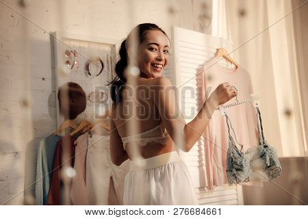 Beautiful Asian Girl Holding Hanger With Lace Bralette And Smiling At Camera