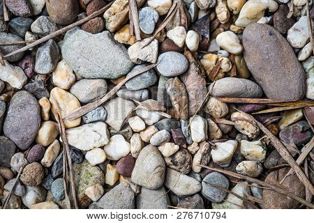 A Top View Of Gravel Or Pebbel Stone And Dry Leaves Background With A Little Sunlight Effect.
