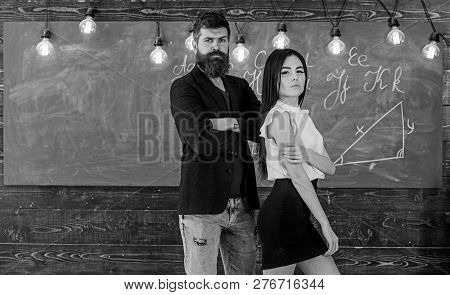 Partners Concept. Man With Beard And Sexy Girl Teacher Stand In Classroom, Chalkboard On Background.