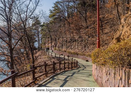 Yesan, South Korea; December, 23, 2018: Two Unidentified People Walking Up Sidewalk In Yesan Lake Pa