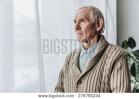 Upset Retired Man With Dementia Disease Standing At Home