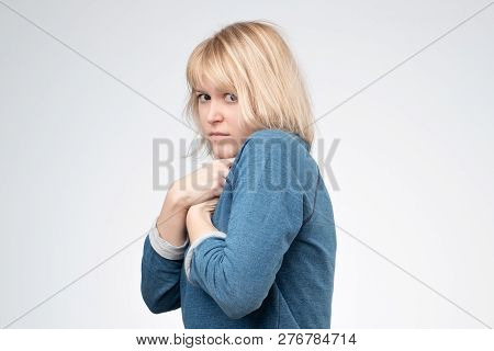A Young European Woman Hides Something In Her Hands And Looks Warily Forward.