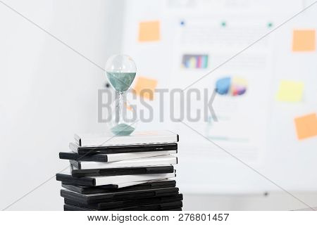 Hourglass On Stack Of Dvds In Light Business Office