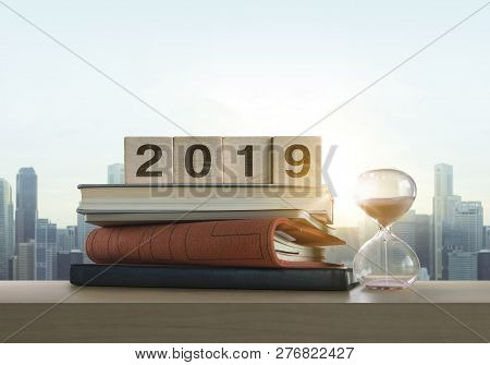 Wooden Blocks With The Word 2019, Notebook, Books And Sand Clock On Table With Panoramic City Skylin