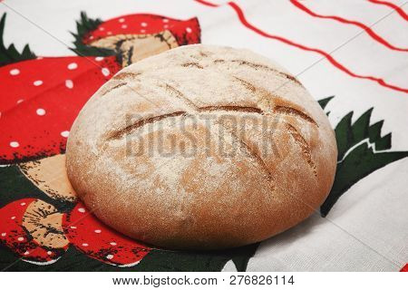 A Loaf Of Round Bread With A Pattern On A Bright Tablecloth