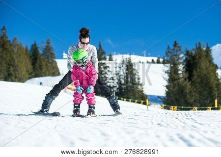 Mother And Little Child Skiing In Alps Mountains. Active Mom And Toddler Kid With Safety Helmet, Gog