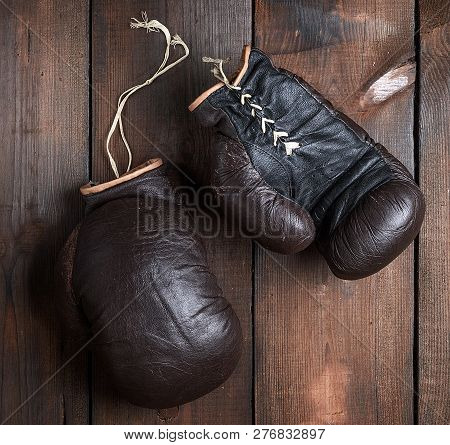 Very Old Brown Boxing Gloves On A Brown Wooden Background, Top View