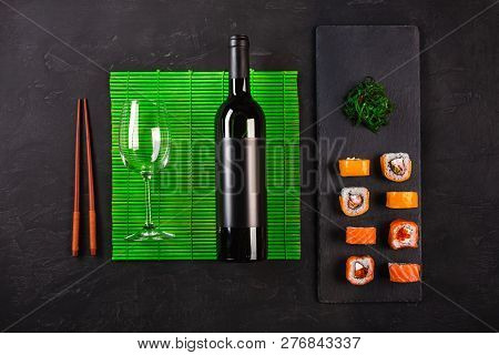 Sushi Set Sashimi And Sushi Rolls, Bottle Of Wine And A Glass Served On Stone Slate