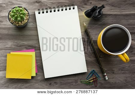 Notebook On Office Table With A Cup Of Coffee, Plant, Stationery And Office Supplies. Blank Notepad 