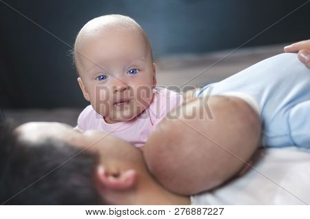Young Father With His Newborn Twins Lying In Bed. Selective Focus