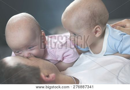 Young Father With His Newborn Twins Lying In Bed. Selective Focus