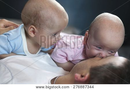 Young Father With His Newborn Twins Lying In Bed. Selective Focus