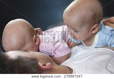 Young Father With His Newborn Twins Lying In Bed. Selective Focus