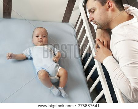Young Dad Is Tired Of Putting A Small Child To Bed. Dad And Son Fatherly Care Concept. Selective Foc
