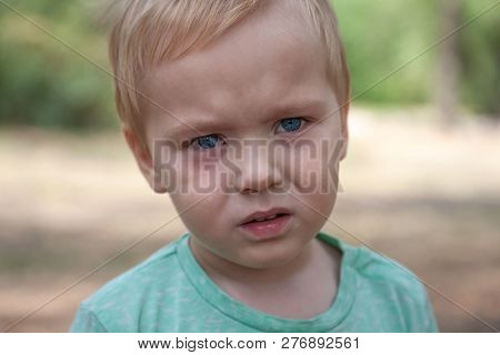 Close Up Portrait Of Cute Caucasian Baby Boy With Serious Expression In Blue Eyes. Moment Of Tears. 