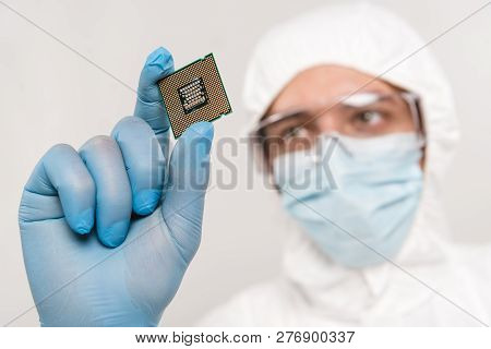 Selective Focus Of Microchip In Hand Of Scientist Wearing Latex Glove And Googles Isolated On Grey