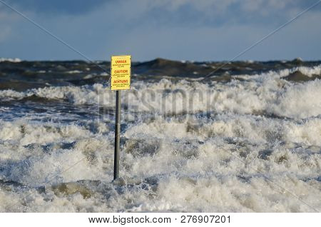 Kolobrzeg, West Pomeranian / Poland - 2019: Blackboard With Danger Warning And Stormy Sea Waves Atta