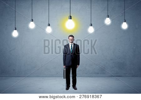 Handsome businessman in an empty space with bulbs above and uninspired face