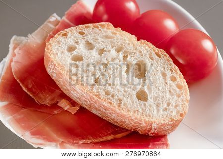 Dry Spanish Ham, Jamon, Italian Ham, Chopped Layers With Bread And Cherry Tomatoes On A White Heart-