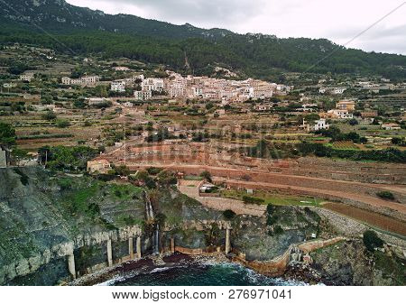 Aerial View Of Coastal Small Hillside Banyalbufar Town On West Coast Mallorca. Surrounded By Tramunt