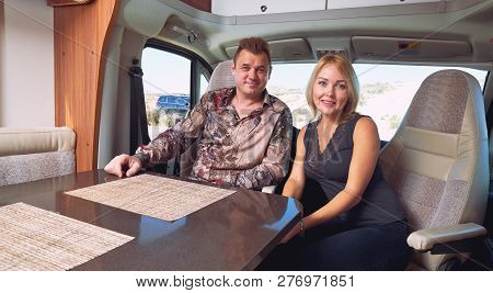 Married Middle Age Couple Sitting Inside Of Recreational Vehicle Looking At Camera. Active People Li
