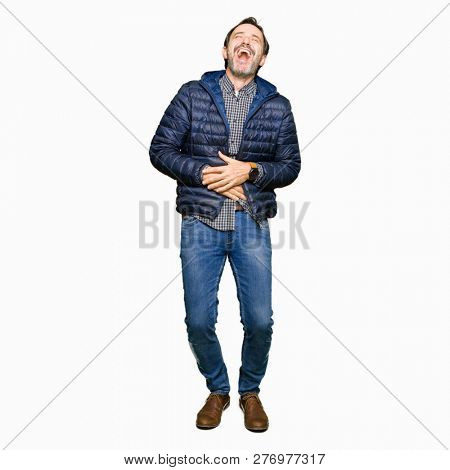 Middle age handsome man wearing winter coat Smiling and laughing hard out loud because funny crazy joke. Happy expression.