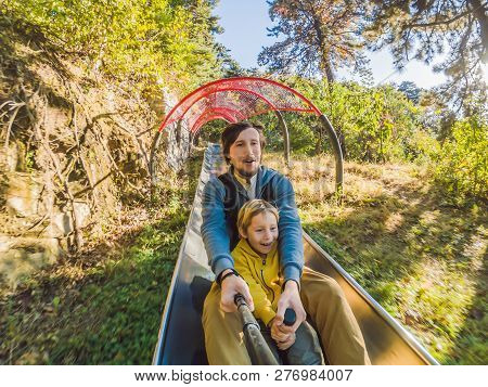 Dad And Son Have Fun On Alpine Roller Coaster
