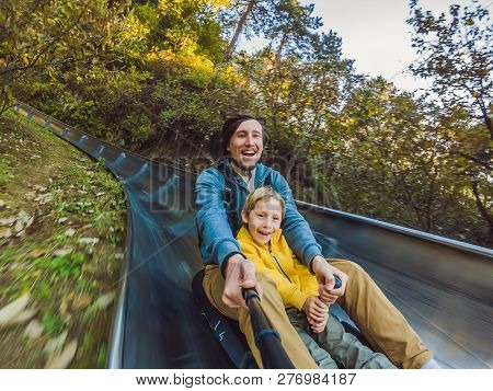 Dad And Son Have Fun On Alpine Roller Coaster