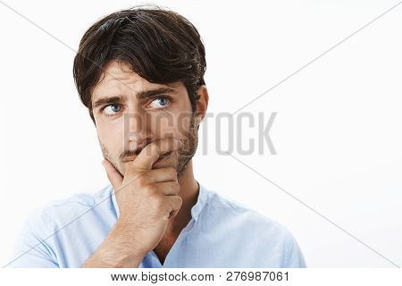 Thoughtful Concerned Young Entrepreneur With Deep Blue Eyes And Bristle Holding Hand On Jaw Looking 