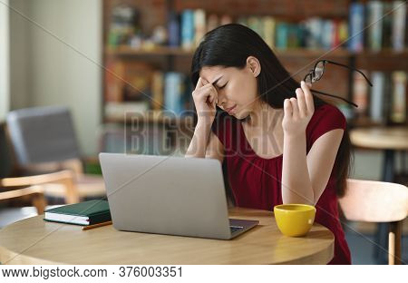 Eyes Fatigue. Asian Girl Rubbing Nosebridge And Taking Off Glasses Tired After Working On Laptop In 